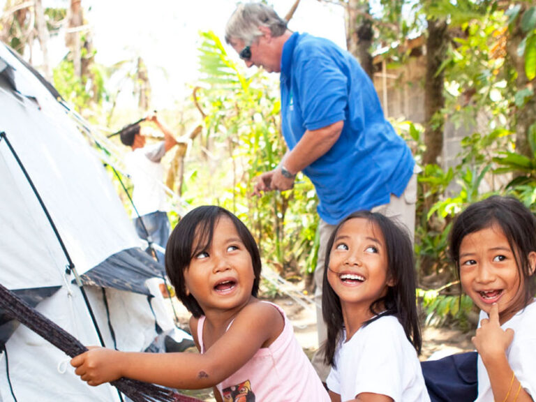 Three girls in hammock in the philippines next to a ShelterBox tent