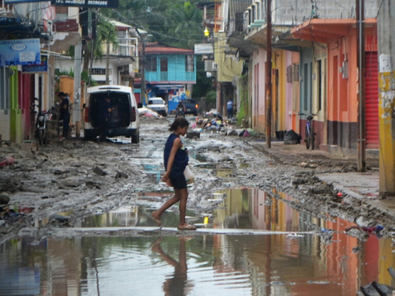 A woman walks on a flooded street in Honduras