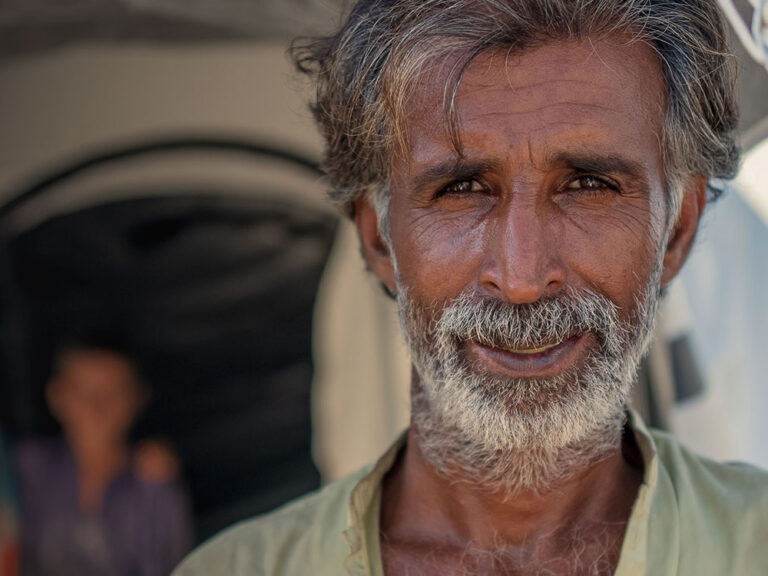 Portrait of Pakistani man standing outside emergency tent