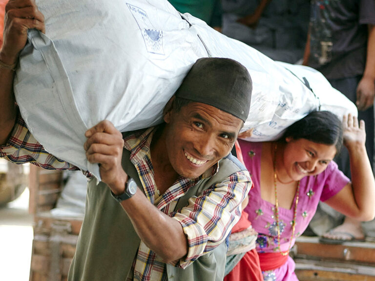 Man and woman carrying a bag of aid in Nepal