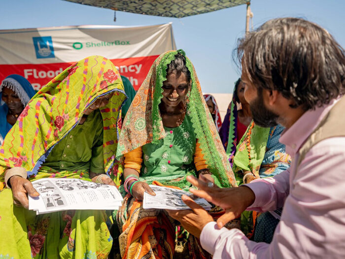 Man speaking to two women who are looking at paperwork in Pakistan