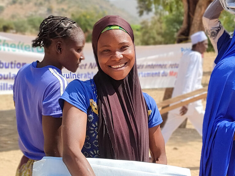 Woman holding aid and smiling in Cameroon