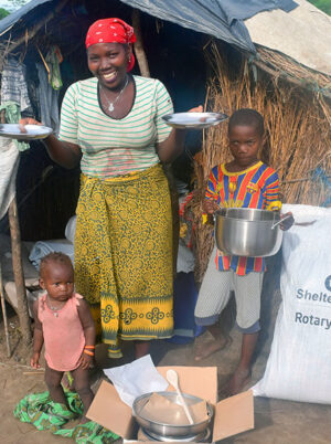 Woman and children holding a kitchen set outside a shelter in Mozambique