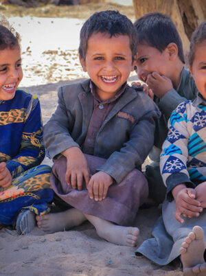 Children sitting on the ground laughing in Yemen