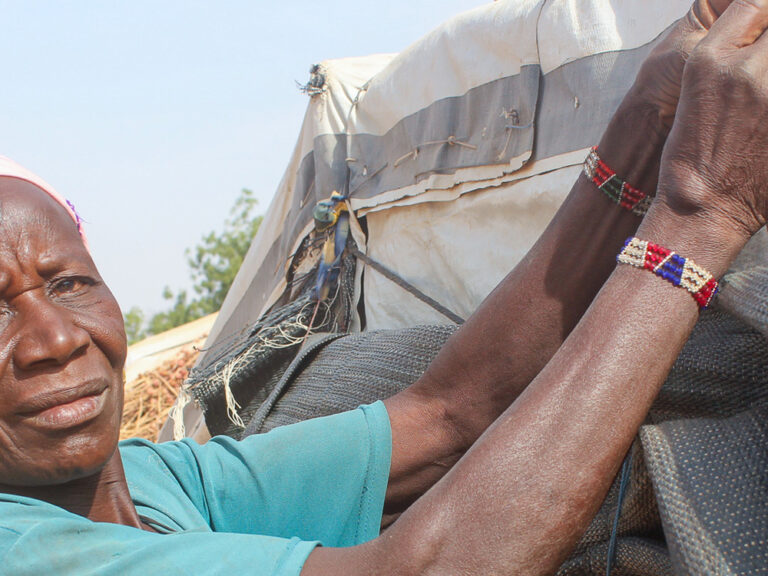 Lady in green tying up a tarpaulin