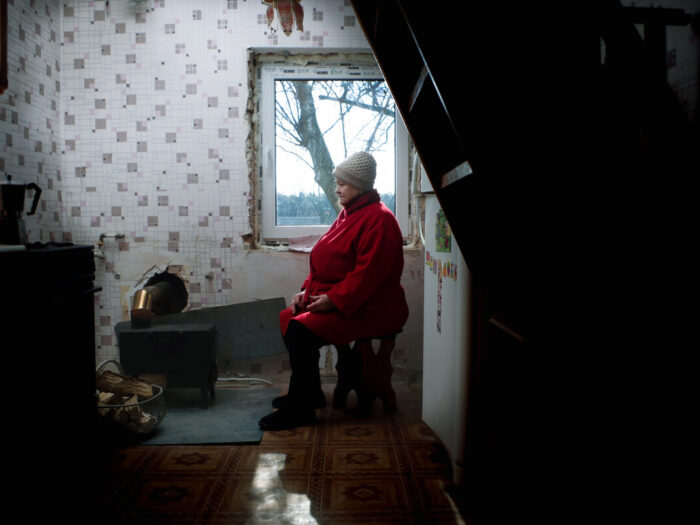 Woman sitting inside a damaged building with a stove in Ukraine