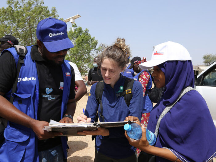 Three people looking at a clipboard in Minawao camp in Cameroon.