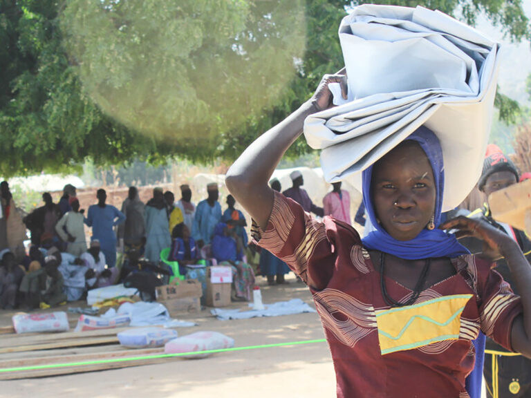 Woman carrying a tarpaulin on her head