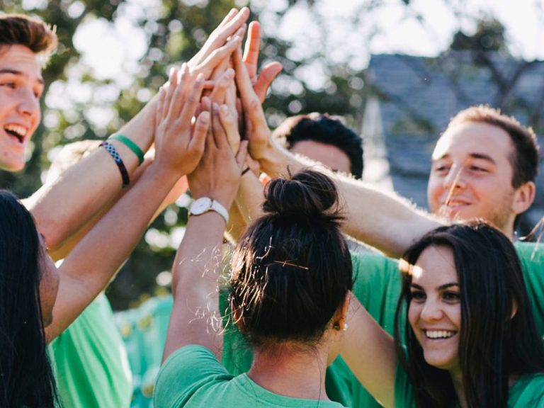 Group of people high fiving while wearing ShelterBox t-shirts